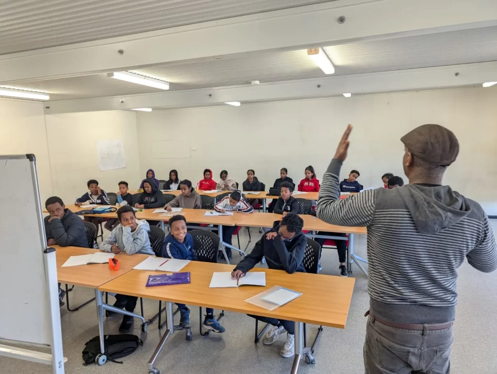 A teacher leading a class of students seated at desks during an ELSP language lesson