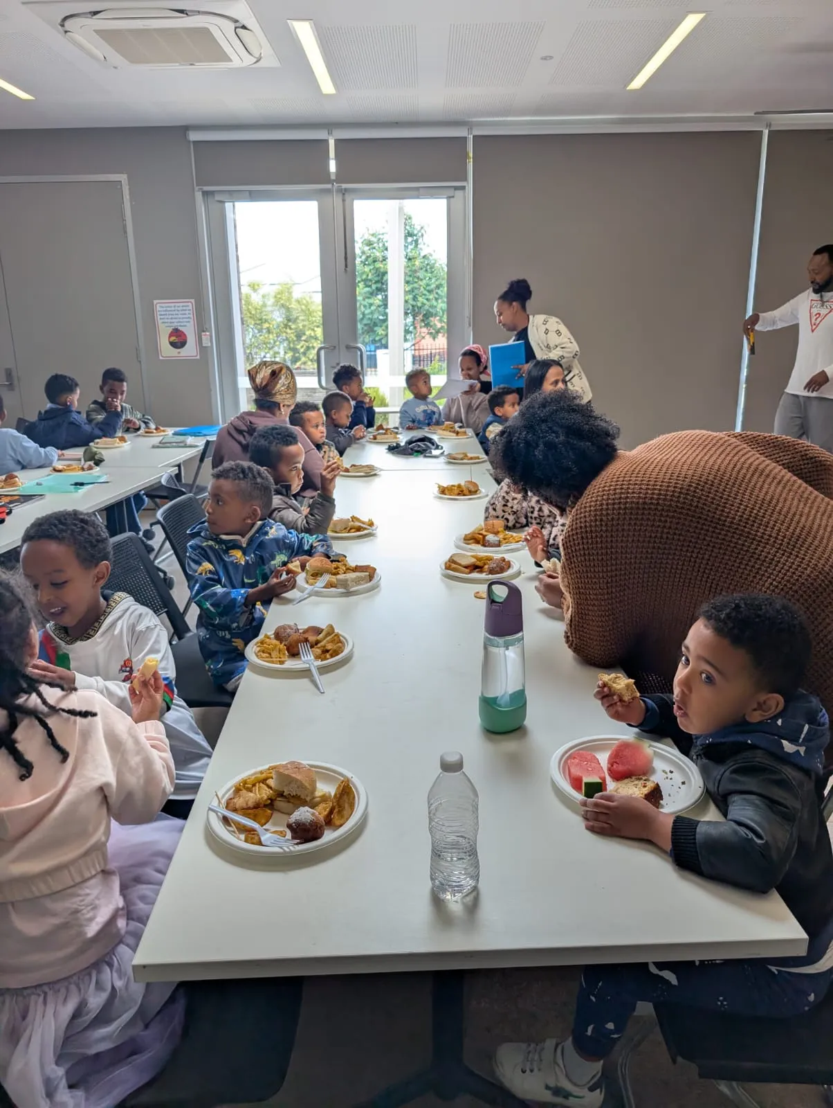 Children seated at long tables sharing a meal at the ELSP end of school celebration