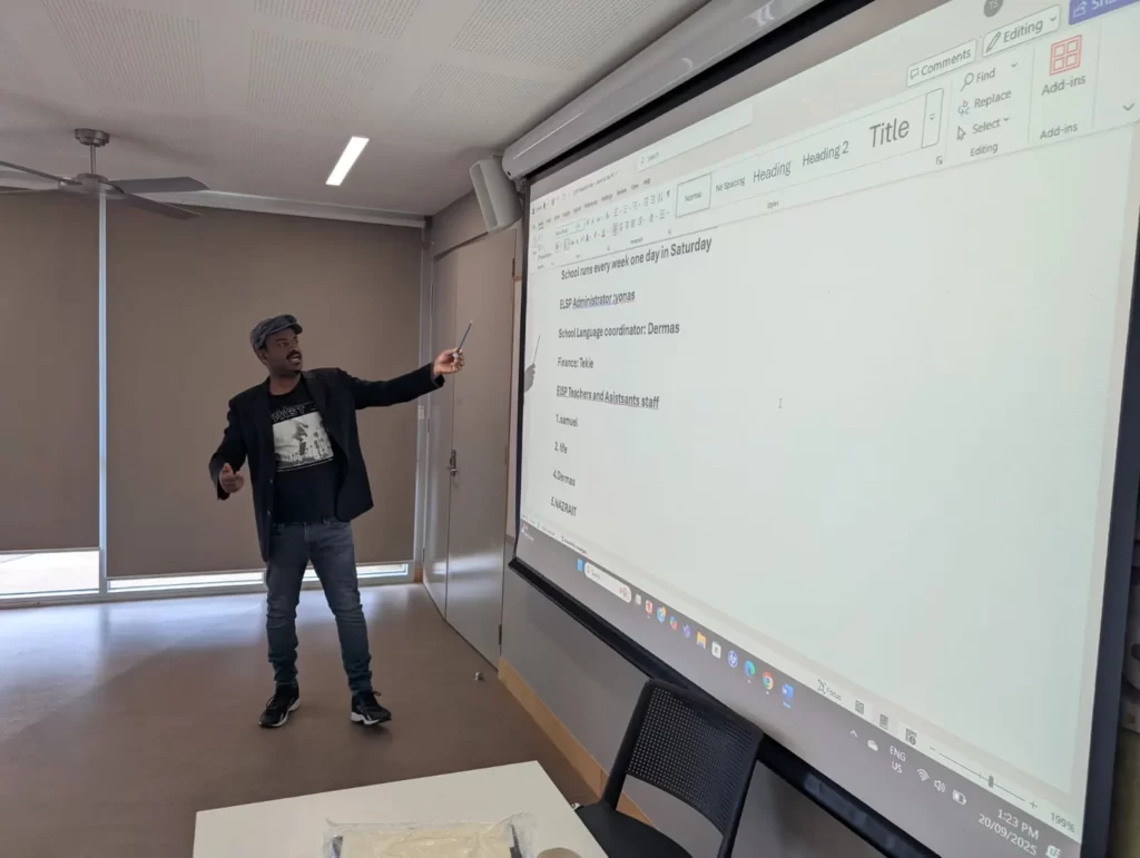 An ELSP coordinator presenting the program’s Saturday schedule and teaching staff on a large screen